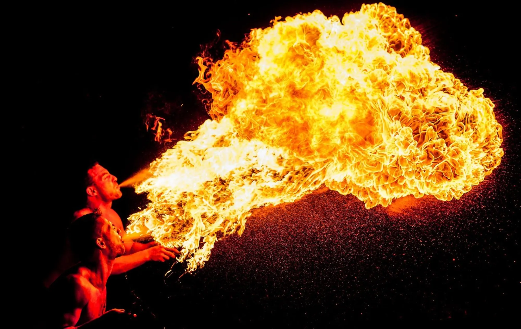 Zwei Feuerkünstler spucken gemeinsam eine große Flamme